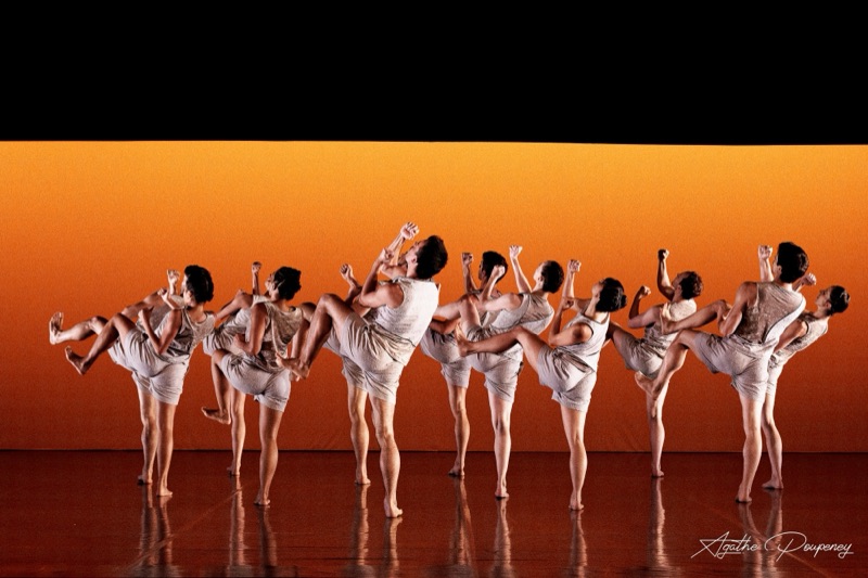Léo Lérus's Ici: dancers of the Ballet de l'Opéra national du Rhin, legs raised, against an orange backdrop